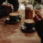 Two people enjoying cappuccinos at a cozy café, creating a warm and inviting atmosphere.